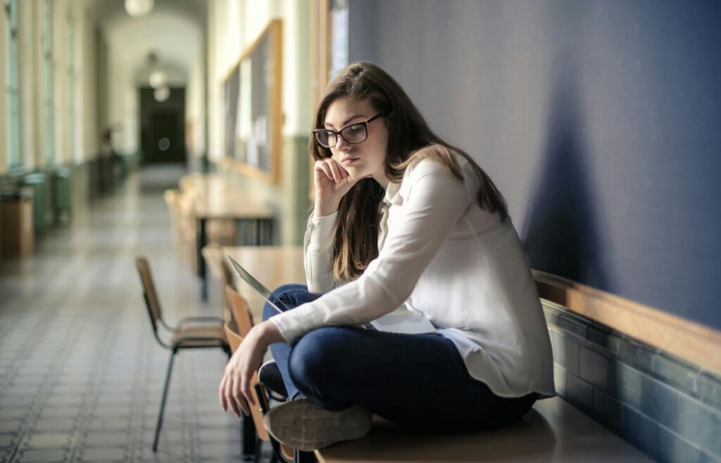 Woman in White Long Sleeve Shirt and Blue Denim Jeans Sitting on Table