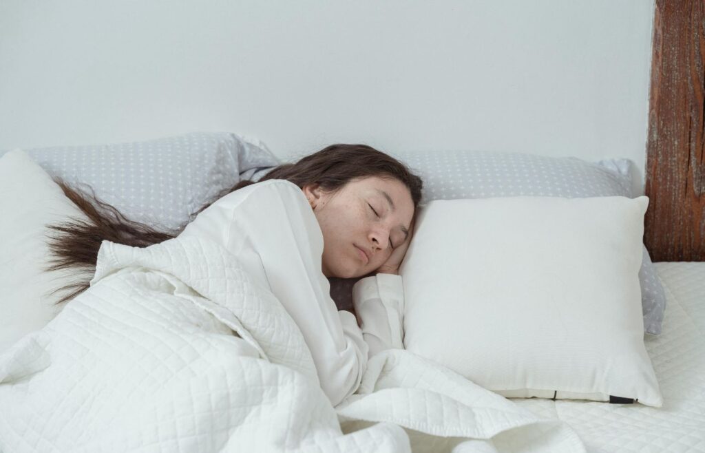 Young woman sleeping on white bed