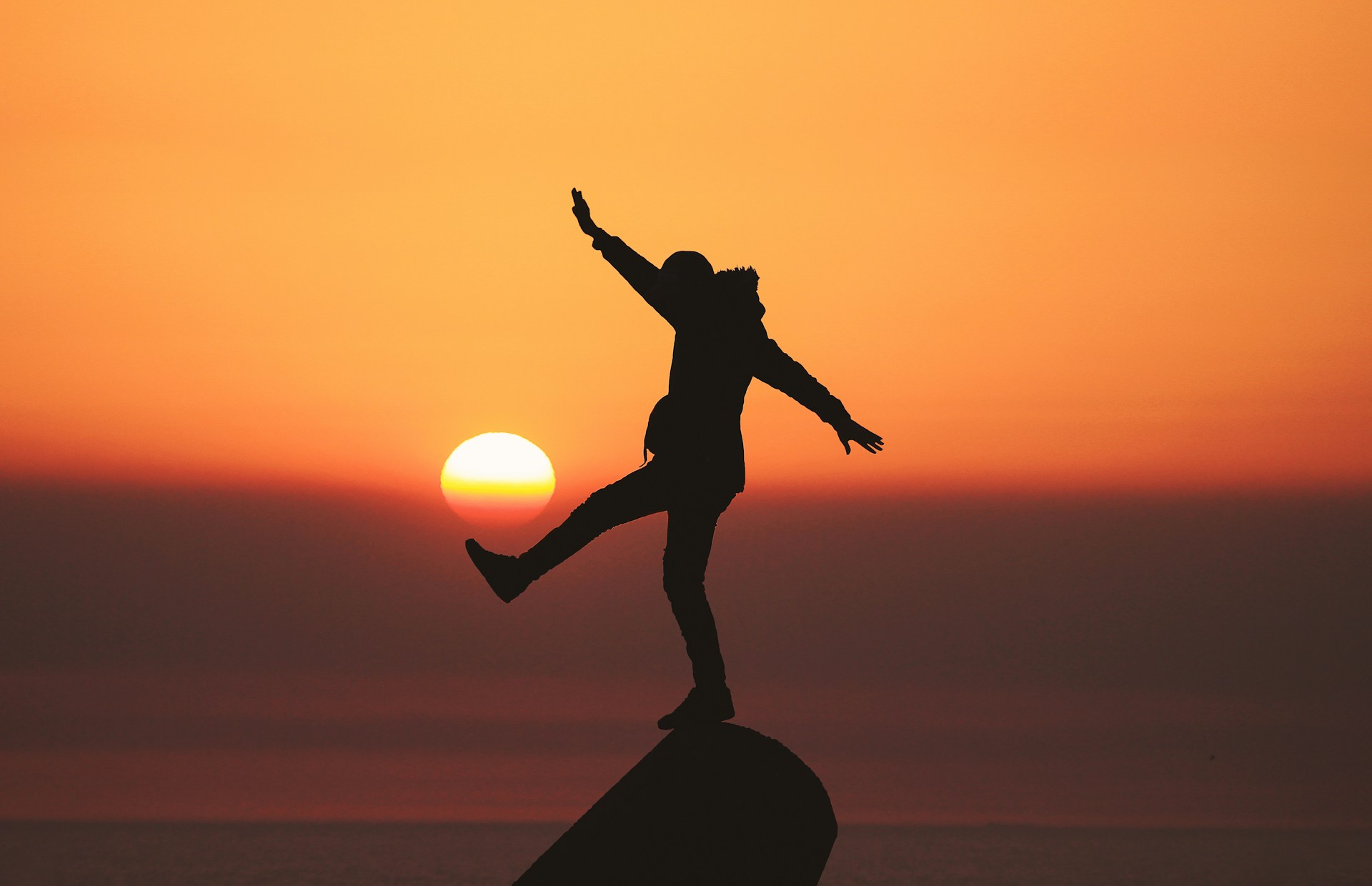 silhouette photo of man standing on rock