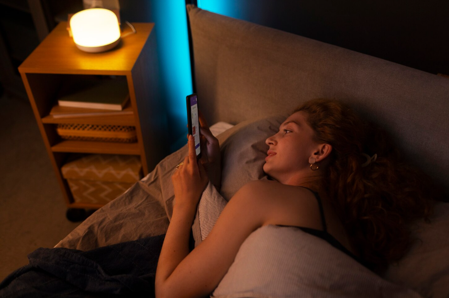 Woman experiencing revenge bedtime procrastination while scrolling on her phone in bed late at night