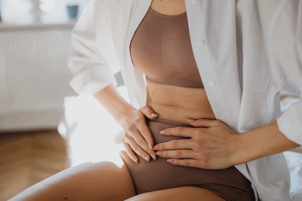Woman at Home Suffering from Menstrual Pain, Having Cramps. Close up of Woman Holding Abdomen, Endometriosis, and Conditions Causing Pain in Tummy.