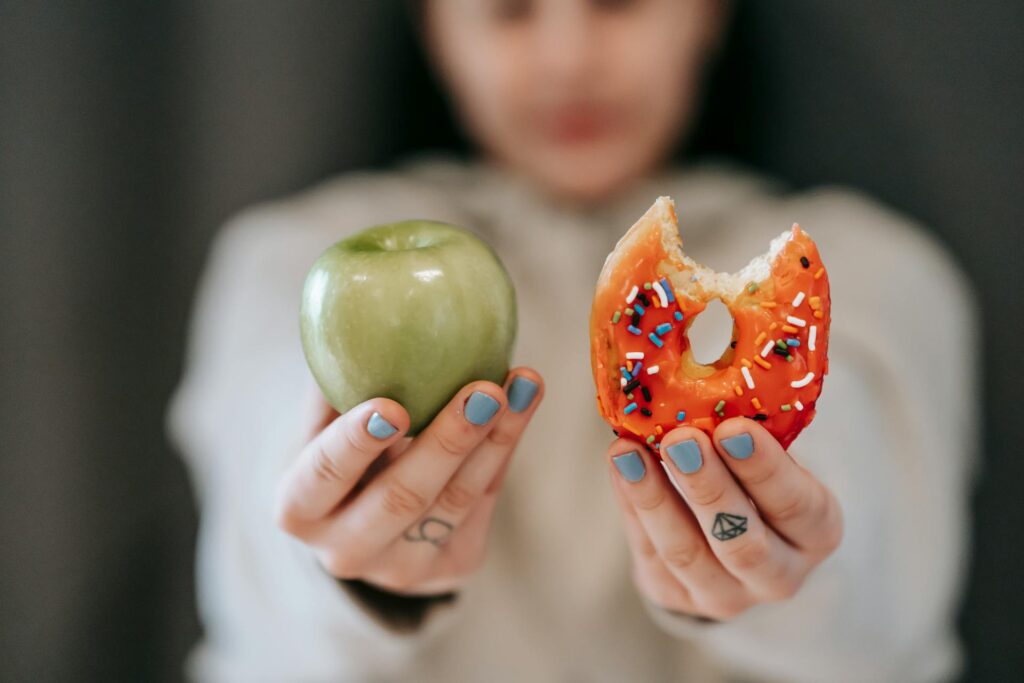 woman showing apple and donut